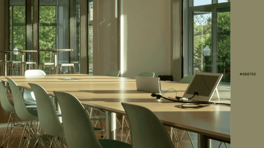 Minimalist conference room with light green chairs, wood table, and tablet accessory