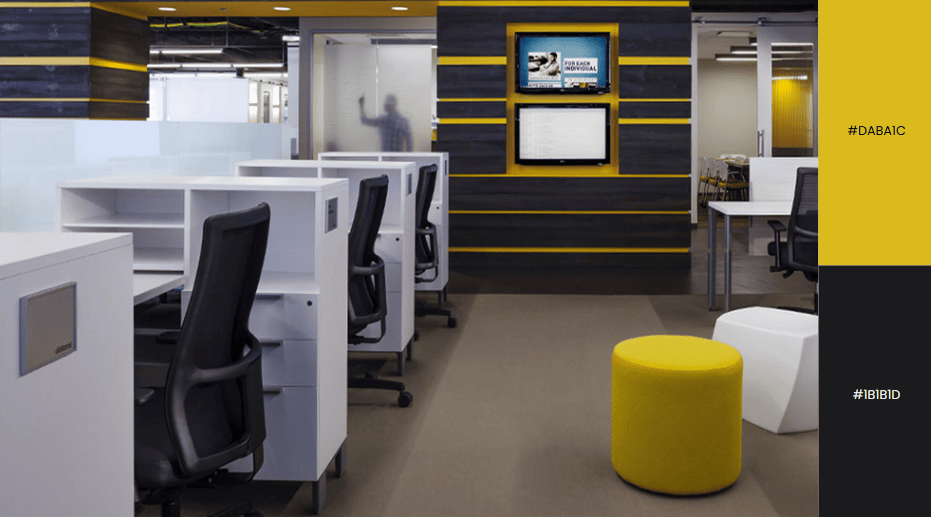 Modern office with yellow accents, white desks, black chairs, and a yellow pouf