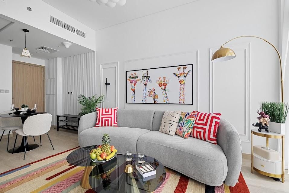 The image features a modern, vibrant living room with a colourful rug, playful giraffe art, and a unique lamp.