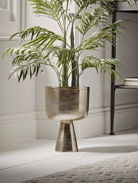 This design features a stylish indoor plant in a metallic planter, enhancing the room's ambiance.