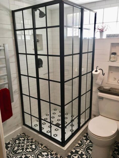 Walk-in shower ideas for small bathrooms with black framed glass enclosure, white subway tiles, and patterned floor tiles.