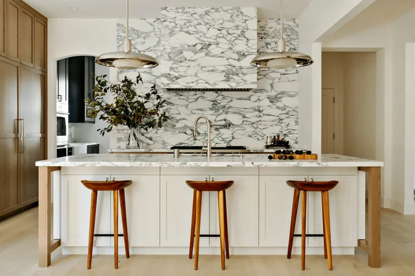 marble effect kitchen wallpaper behind a family kitchen island with wooden stools